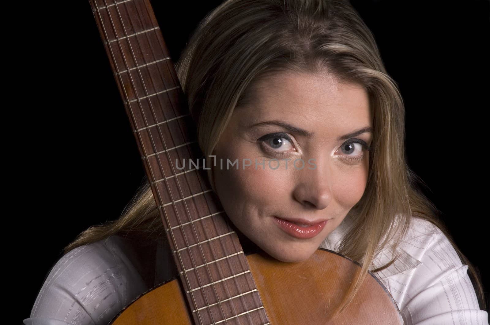 Attractive smiling female guitarist leaning on guitar thinking over a black background