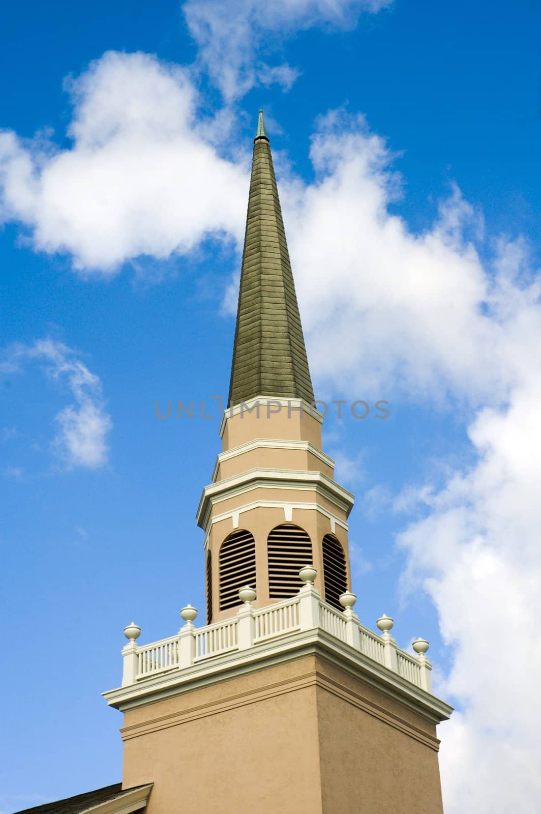 Close up of a small town church steeple against a blue sky with clouds