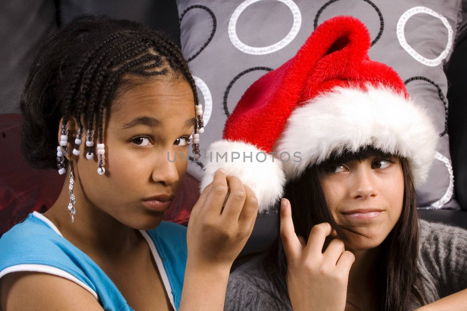 cute african american girl holding santa hat of caucasian girl freind