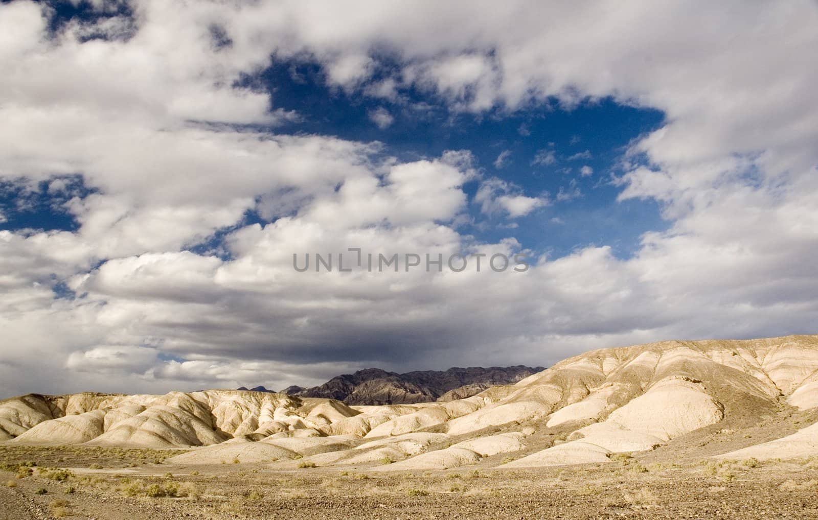 desert ecenery with hills lit by the setting sun and stornm clouds overhead