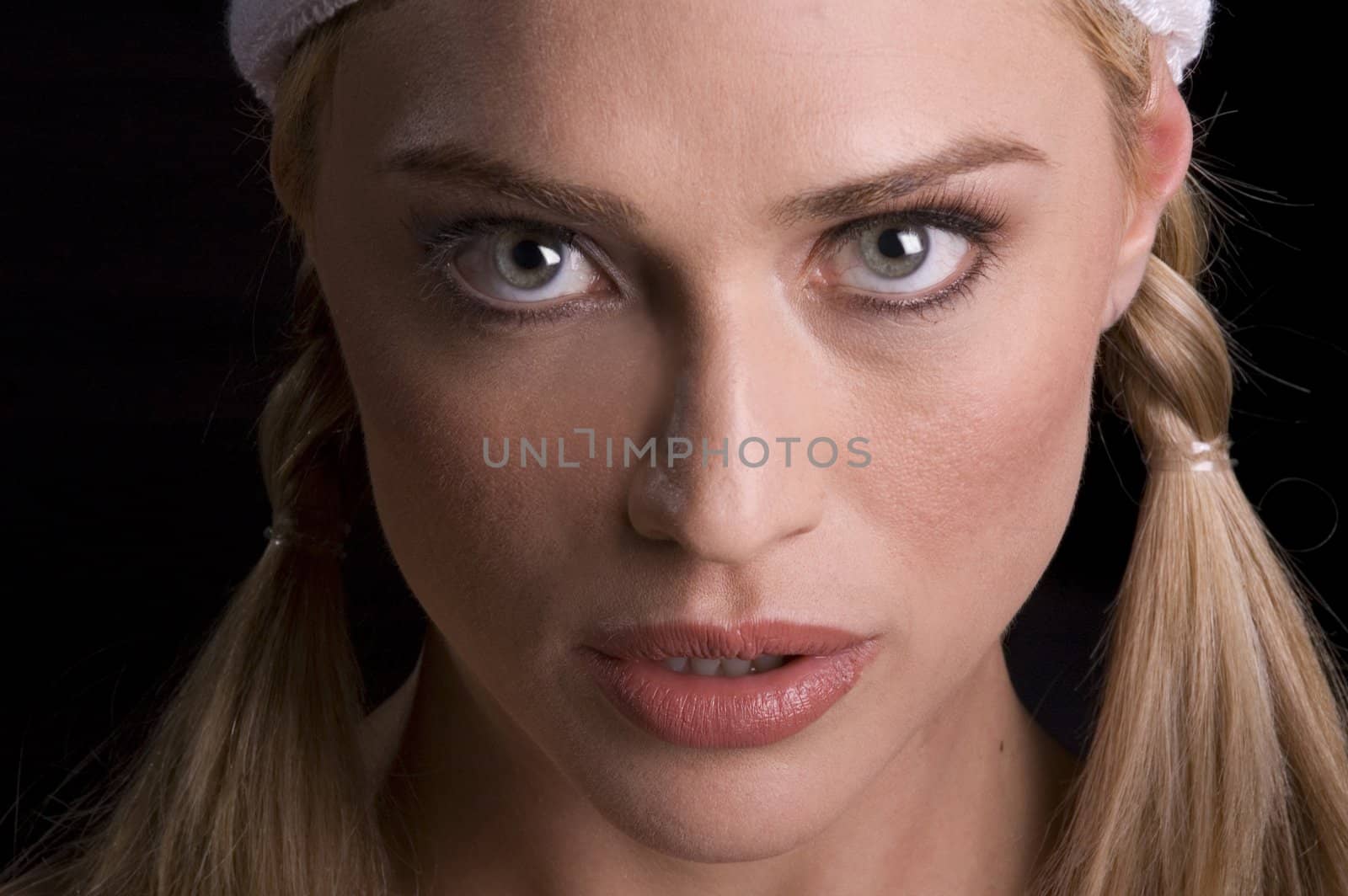 closeup of woman in sweatband and ponytails ready for sports on a black background