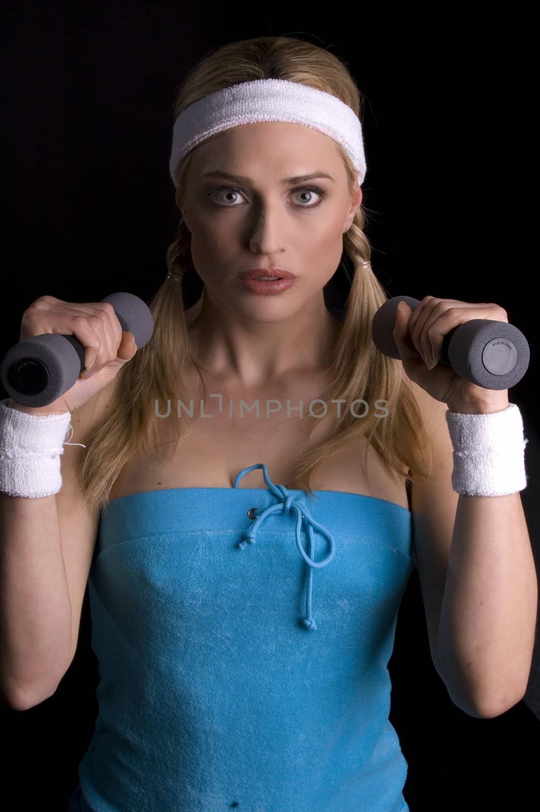 Woman doing exercise weith weights over a black backgound