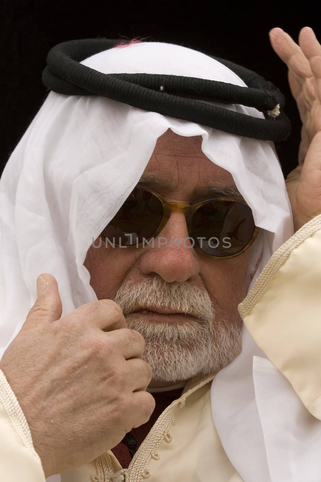 Arabic looking gentleman in a dishdash, traditional headress and wearing sunglasses, making getures during conversation