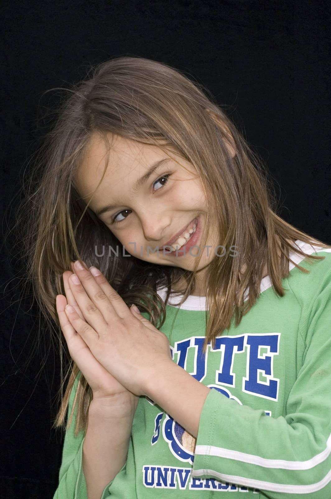 cute caucasian american girl clasping hands together as if praying on black