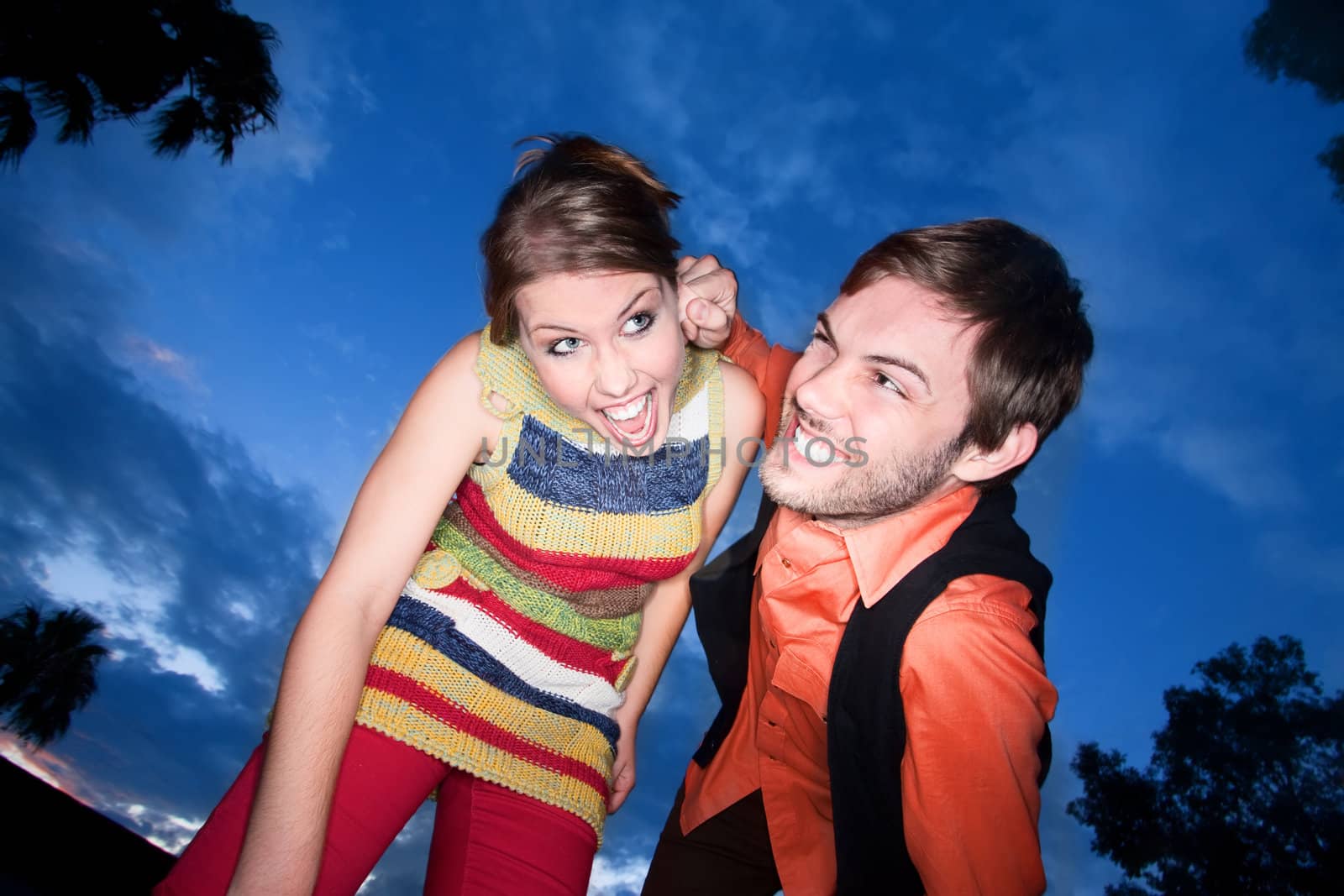 Young couple playing against a deep blue sunset