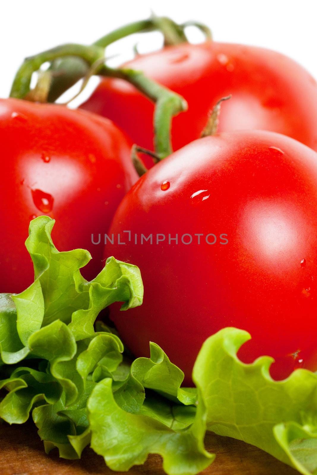 Closeup view of three tomatoes on a lettuce leaf