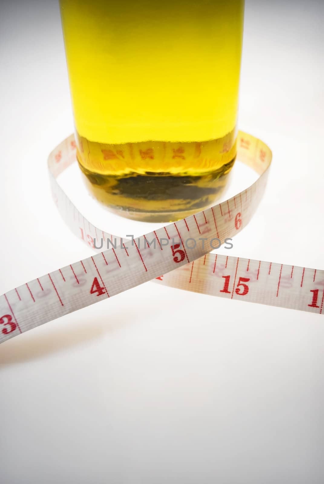 Studio shot of olive oil and measuring tape against white background