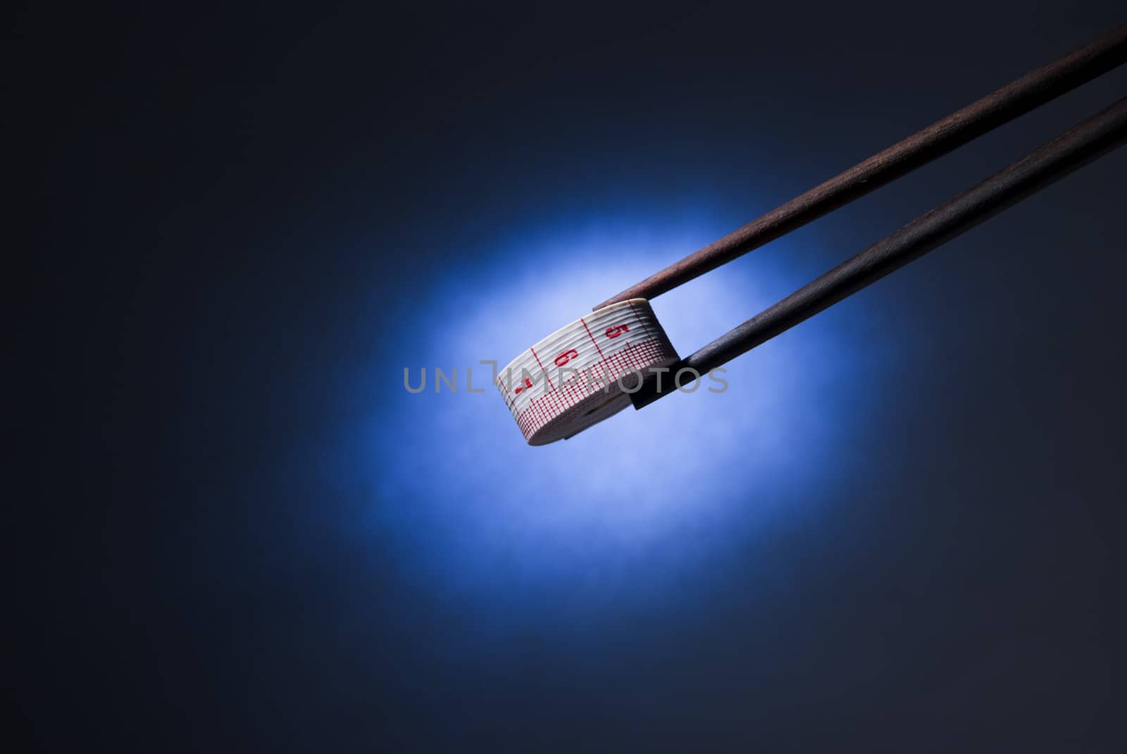 Studio shot of chopsticks holding measuring tape 