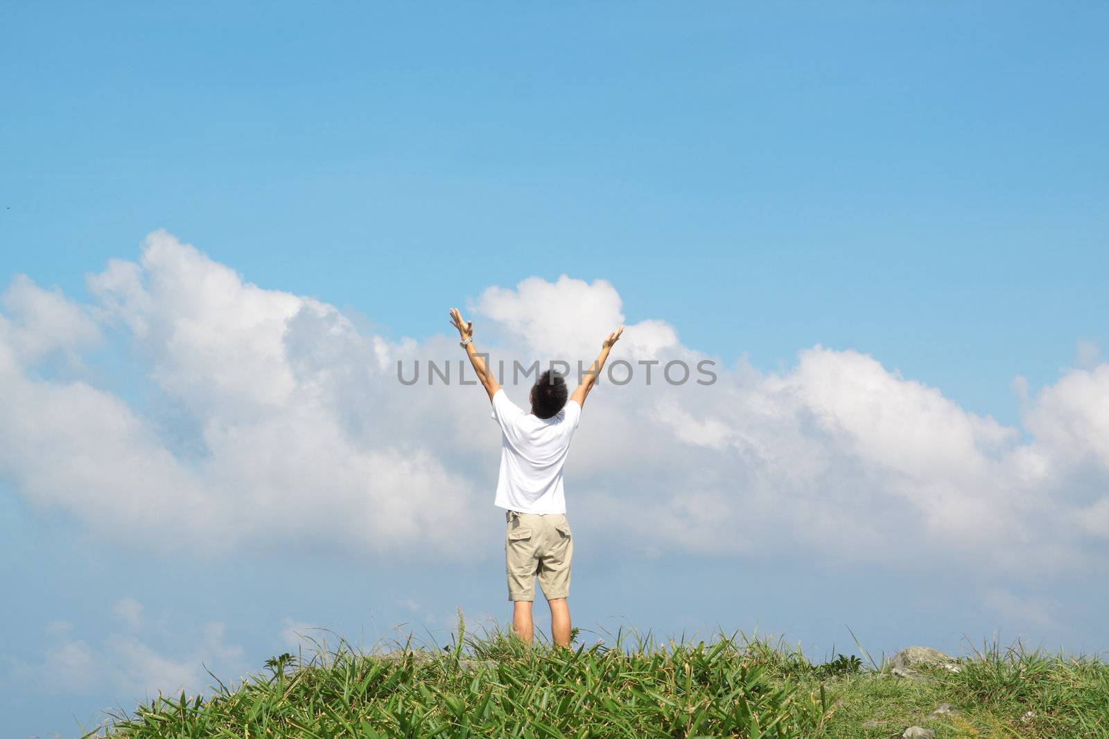 Meeting of the sky. The man on high mountain with the hands lifted above, on a background of blue sky