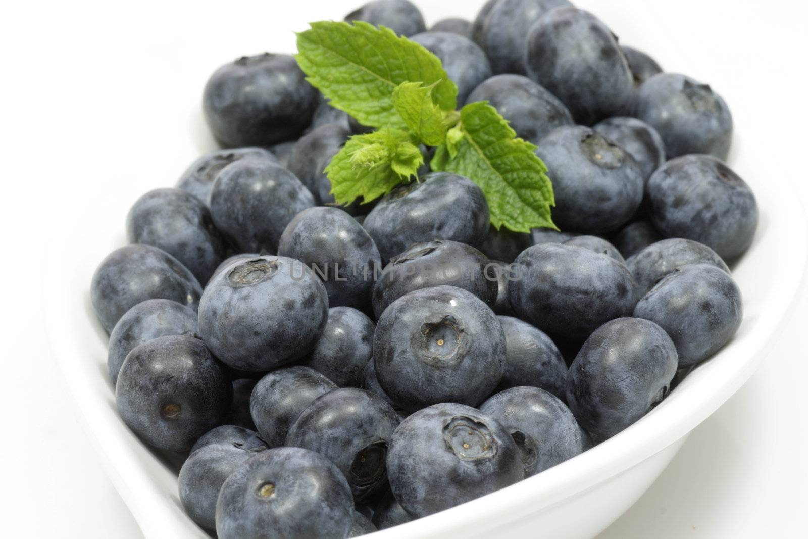 Fresh blueberries with mint leaves in a white bowl