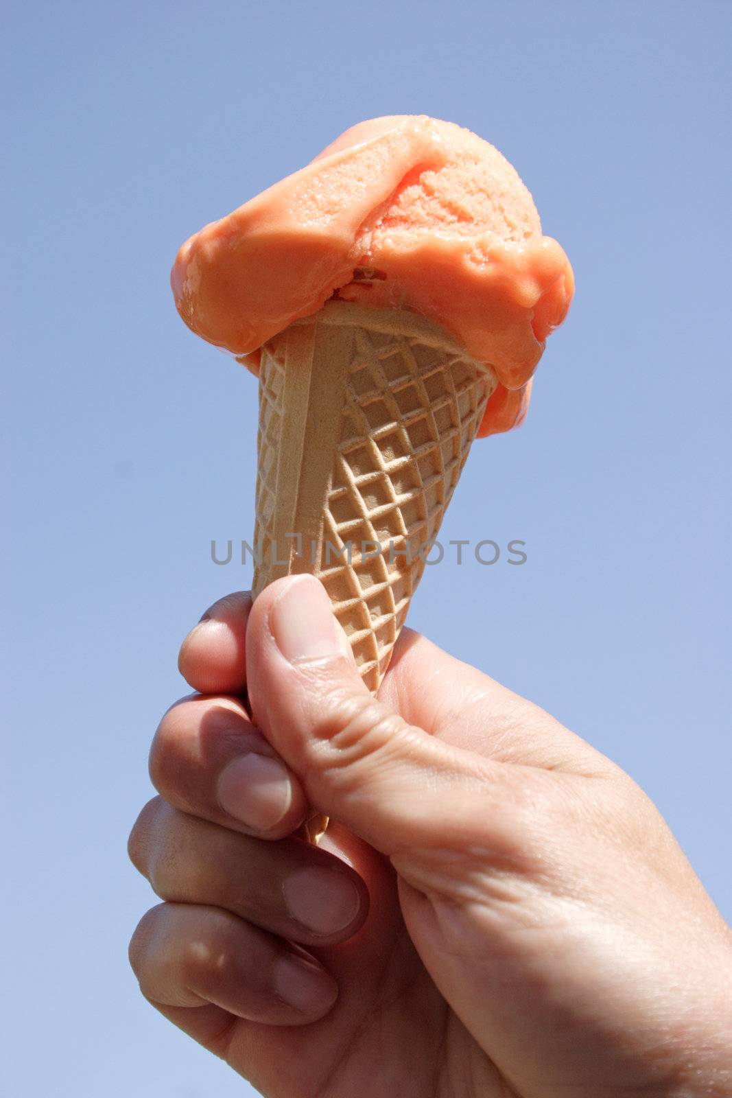 Close-up of an ice-cream in a hand before blue sky