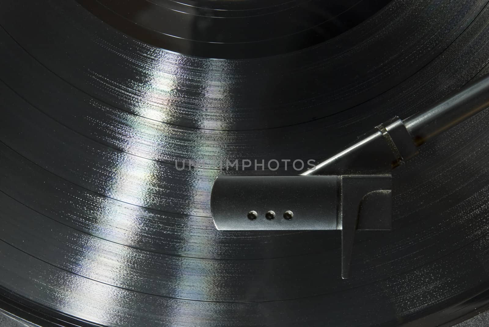 Cropped image shot directly from above of a record player needle, with LP underneath