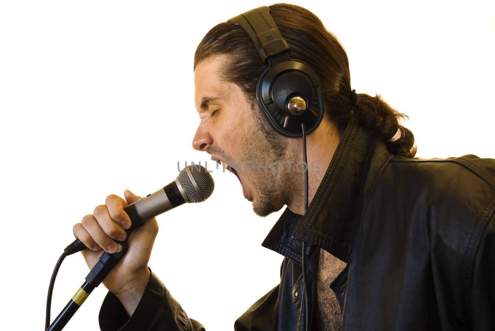Profile of a young man in a leather jacket shouting in a microphone.
