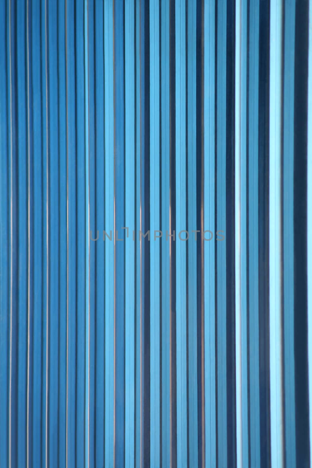 A shot of blue decorative glass tiles partitioning the windows of an office building's facade makes a great gradient background abstract. Vertical version.