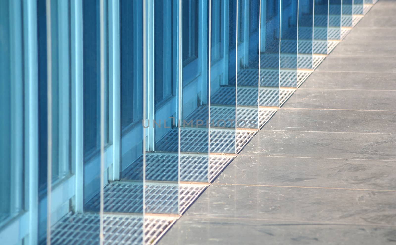 Decorative blue glass plates partition the windows in the ground floor facade of a very modern office building. 