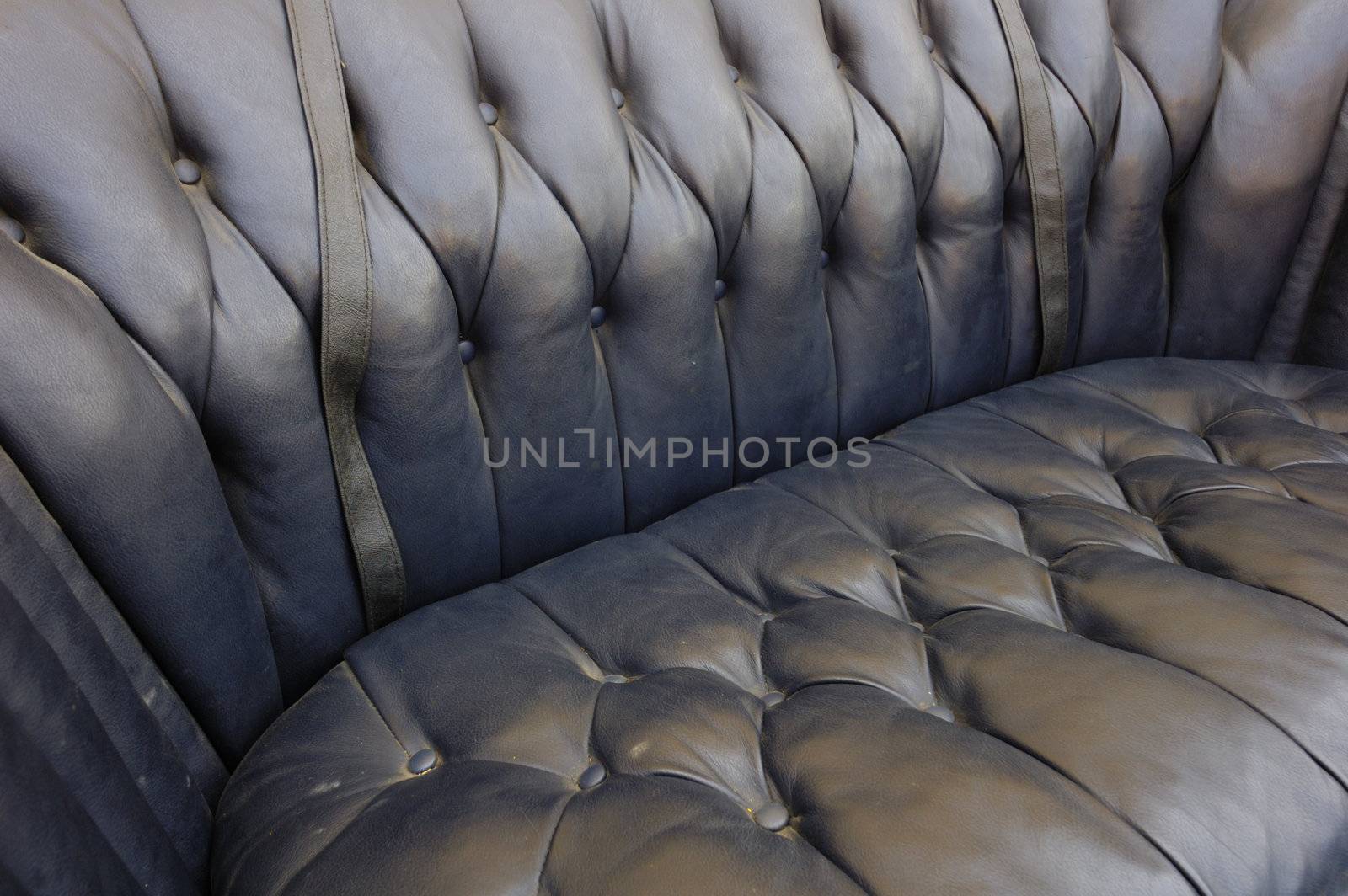Close-up of an old seat upholstered in black leather.