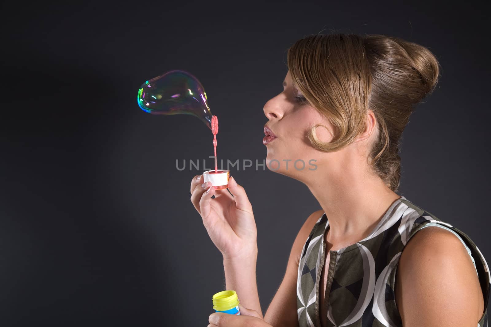 Pretty blond girl with hair in fifties styles blowing soapbubbles