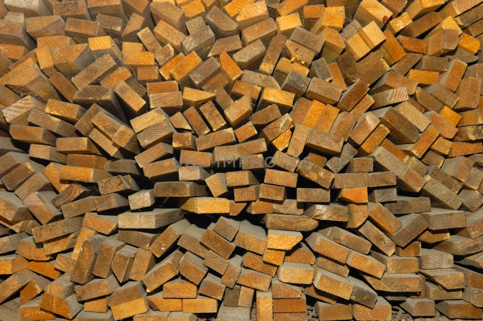 Close-up of the ends of different sizes of cut wood, piled up at a sawmill. Slight wide-angle effect makes pieces appear to radiate from centre.