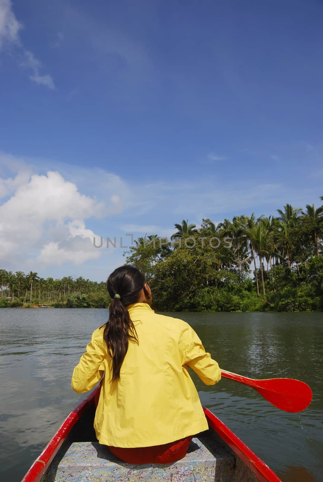 Woman in yellow jacket paddling red canoe