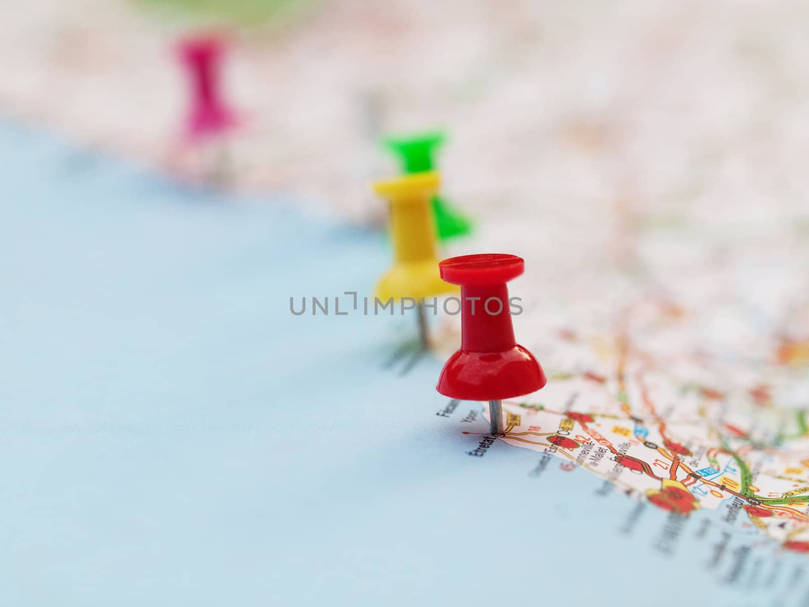 Series of colored pin pointing locations on a french map with selective focus on the red pin