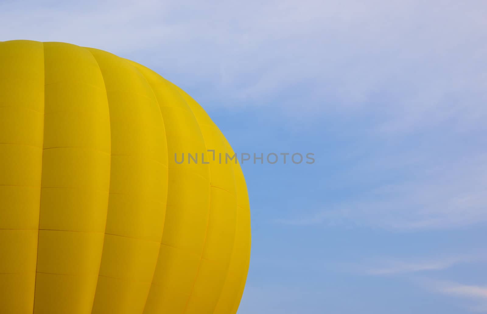 Part of a yellow hot air balloon against a blue sky