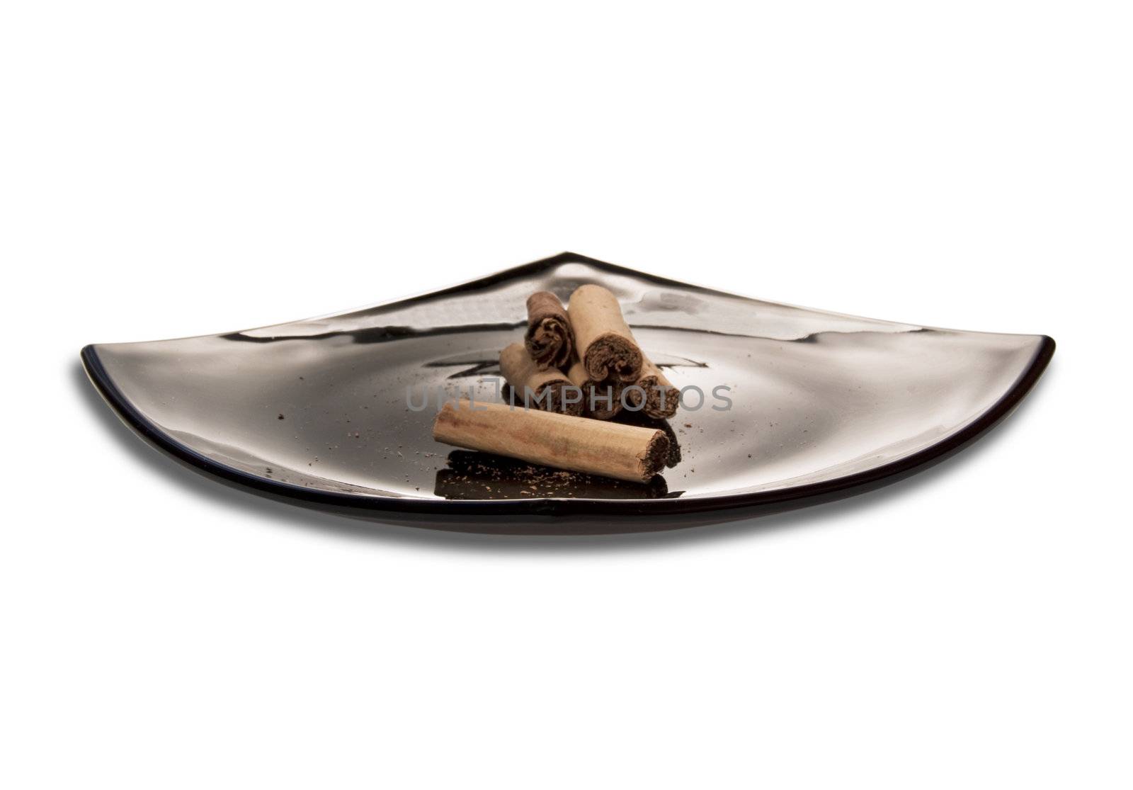 Black plate of cinnamon over a white background