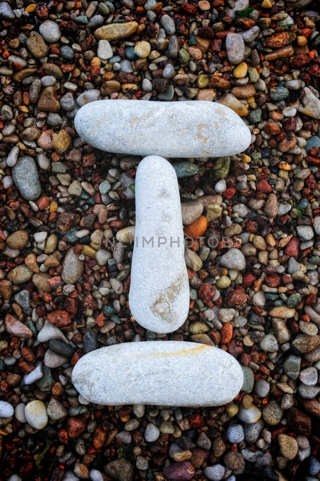 Number "1" form of pebbles, isolated on the background of sea gravel