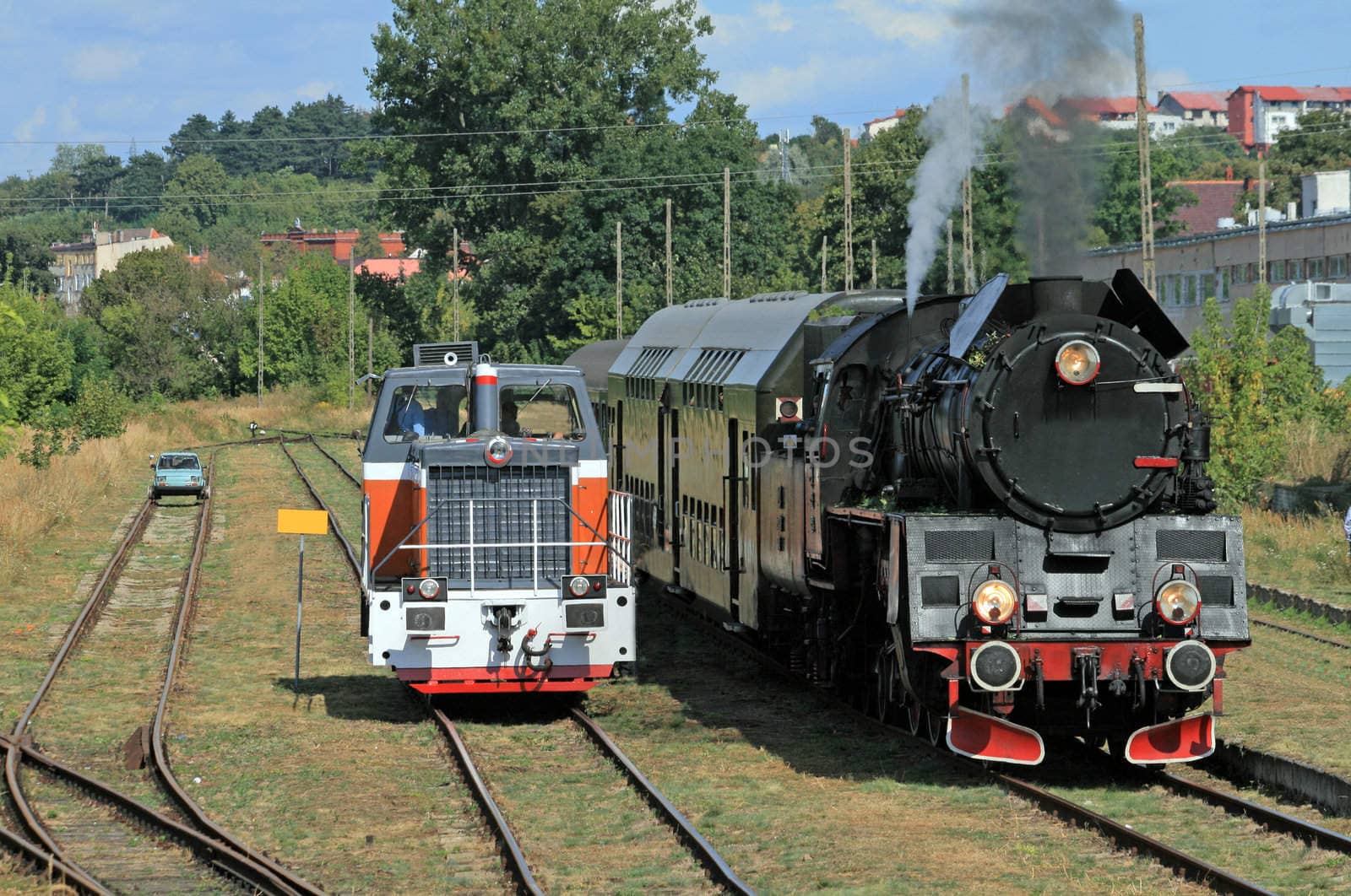 Car, diesel locomotive and old retro steam train standing at the small station

