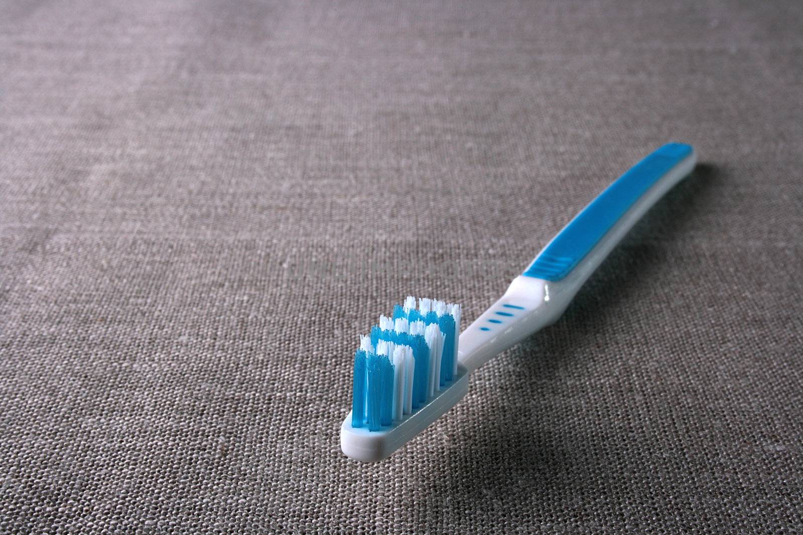 New dark blue tooth-brush on a grey rough fabric.
