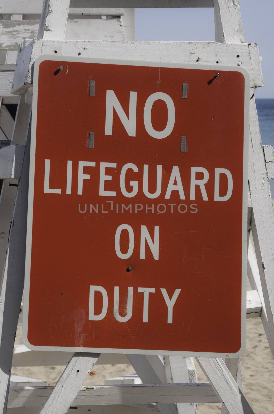 Empty lifeguard tower chair with not on duty sign