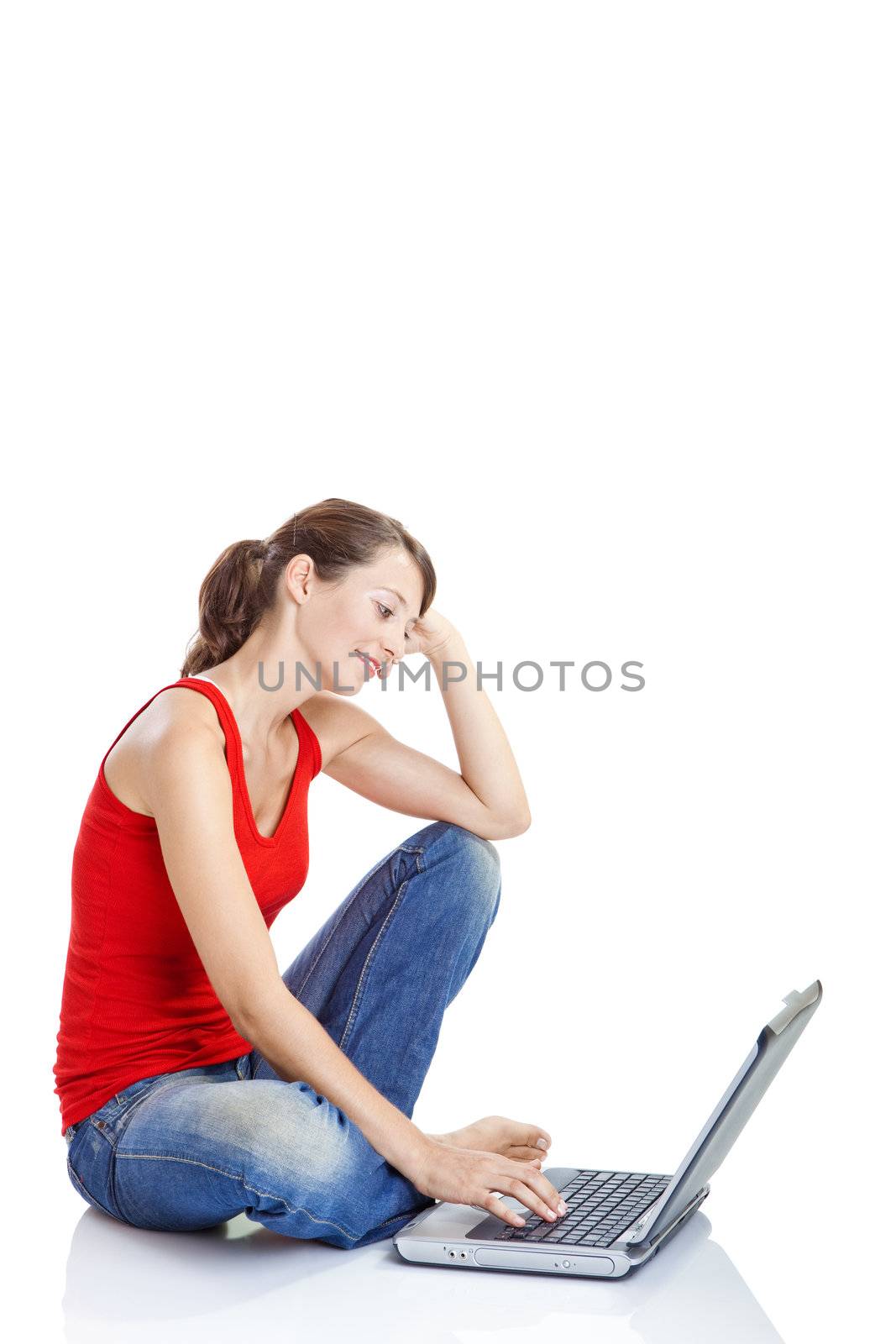 Beautiful and happy young woman sitting on floor and working on a laptop