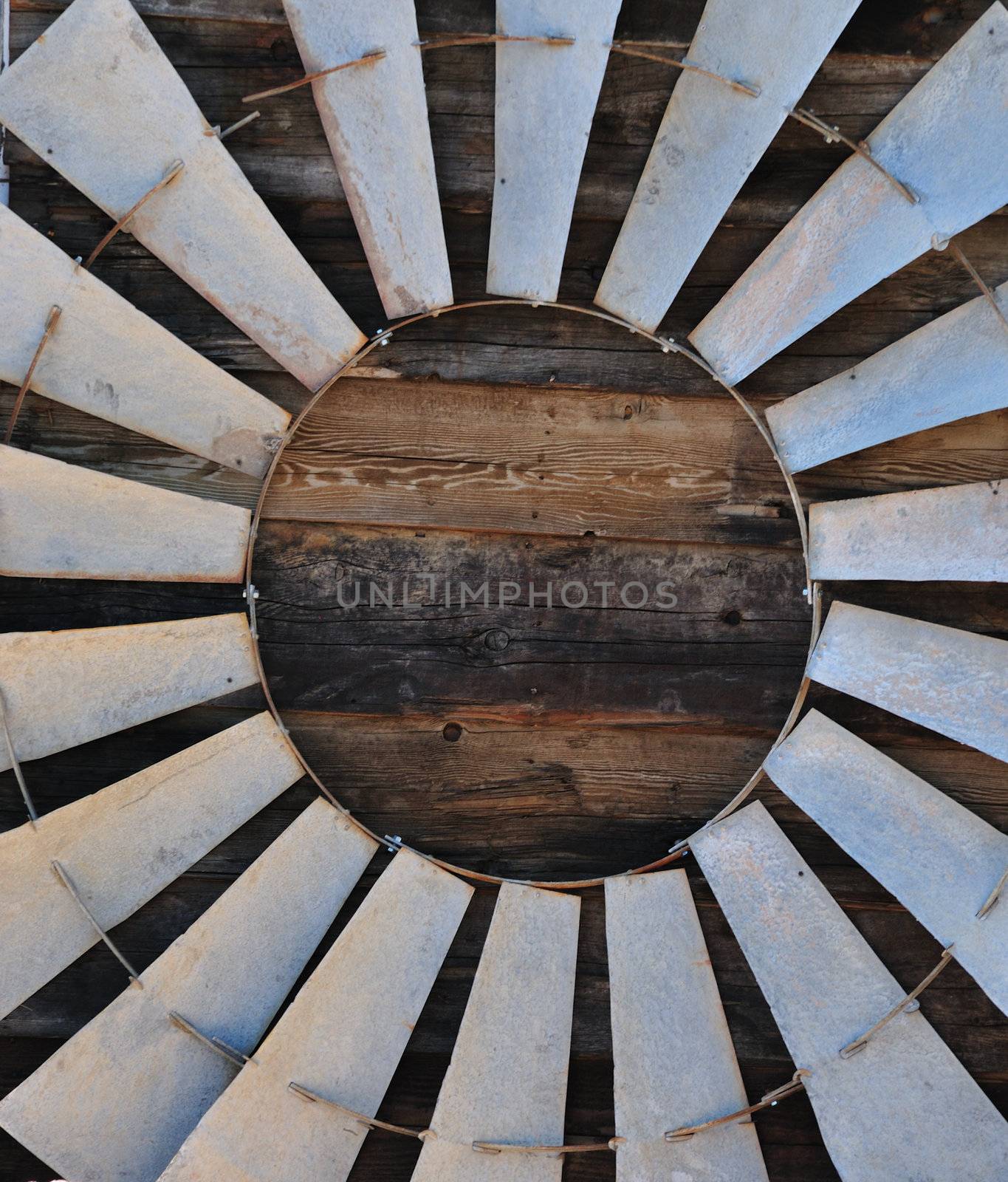 old windmill blade leaning against an old barn wall