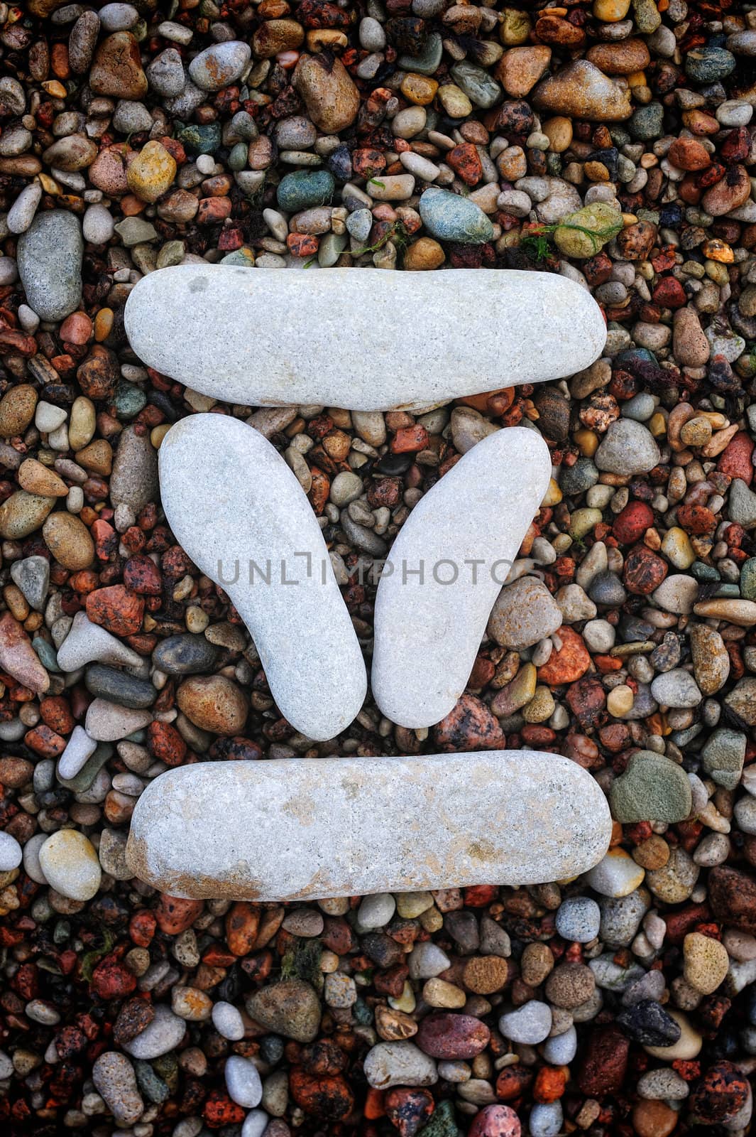 Number "5" form of pebbles, isolated on the background of sea gravel