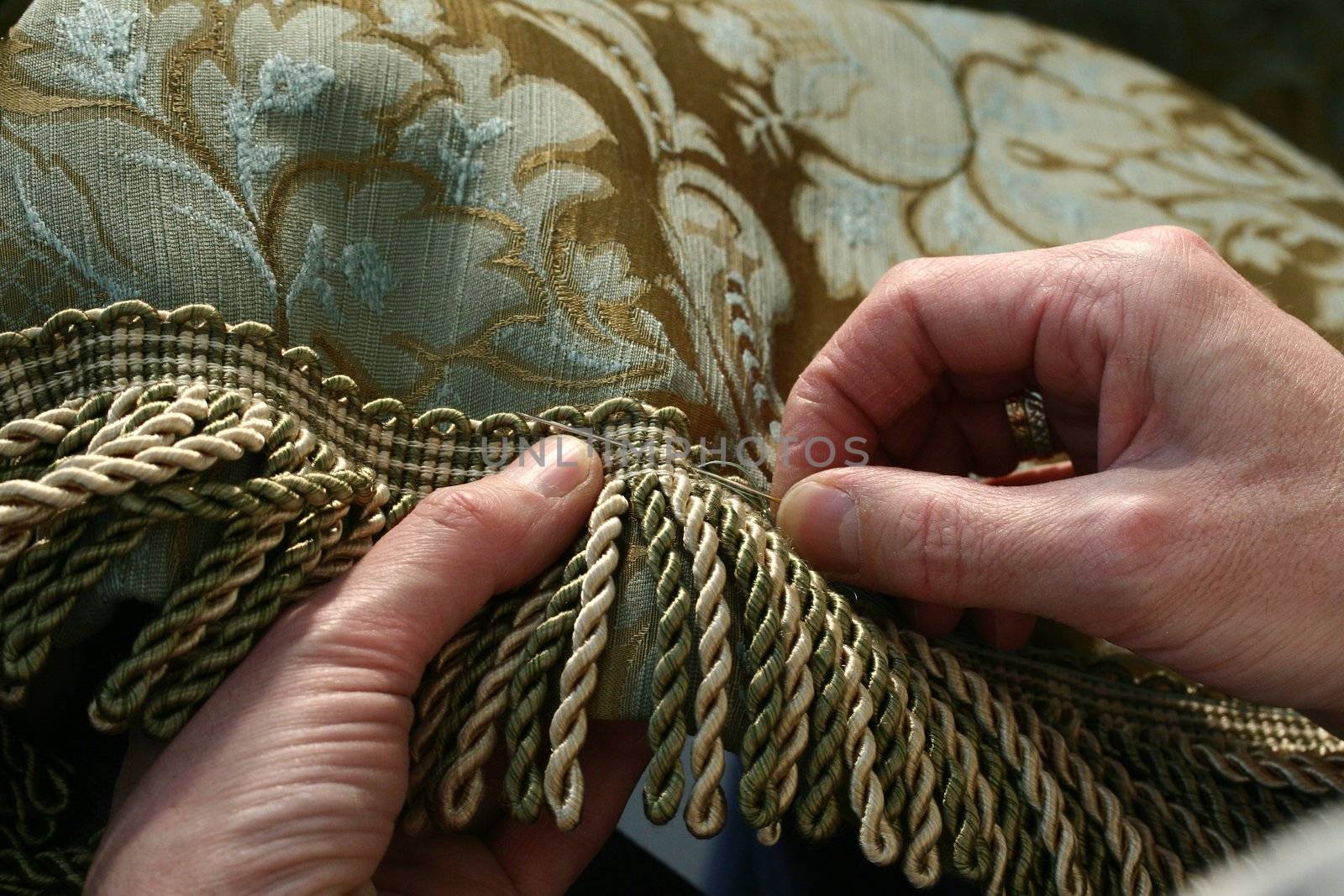 Hands are working on a curtains with needle