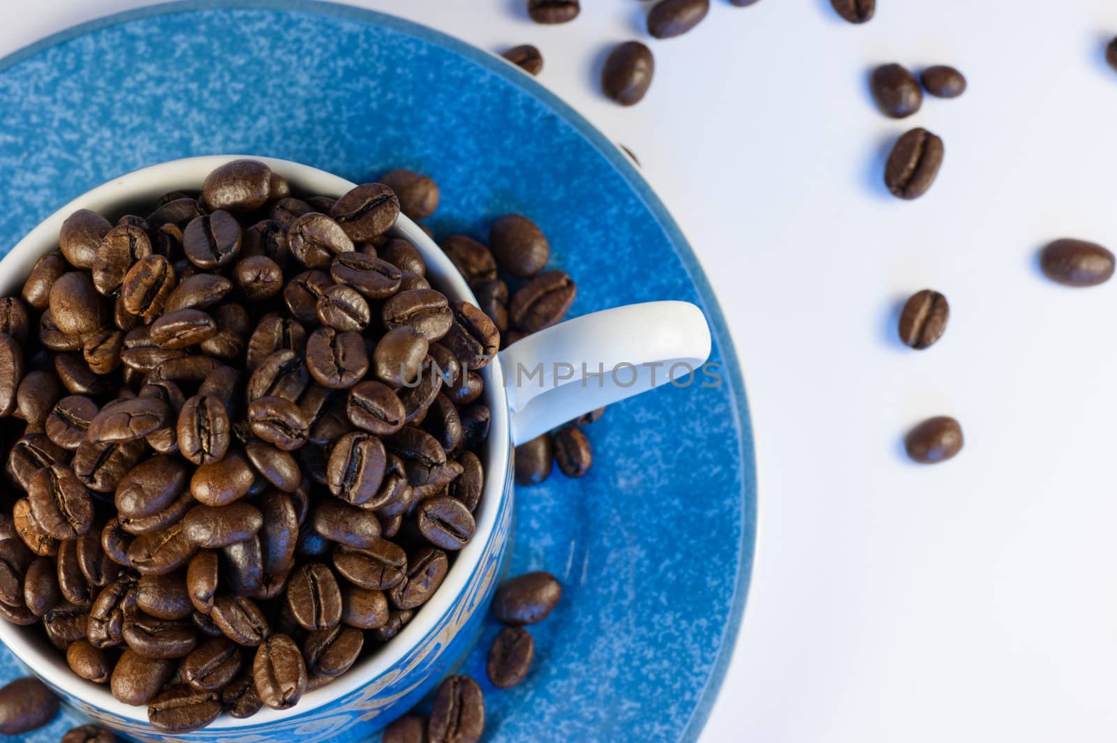 Dark roasted coffee beans in a cup and saucer