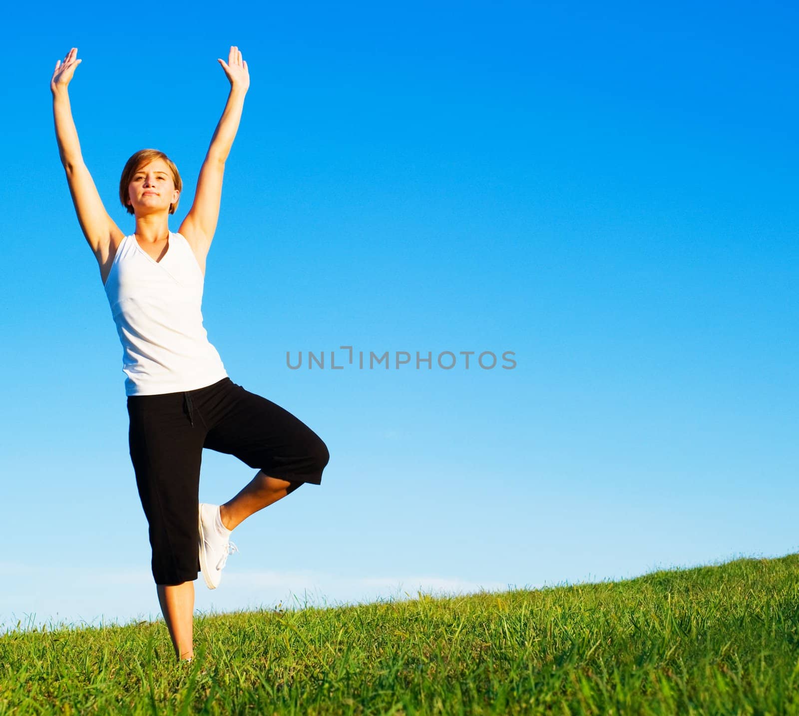 Young woman doing yoga in a sunny meadow, from a complete series of photos.