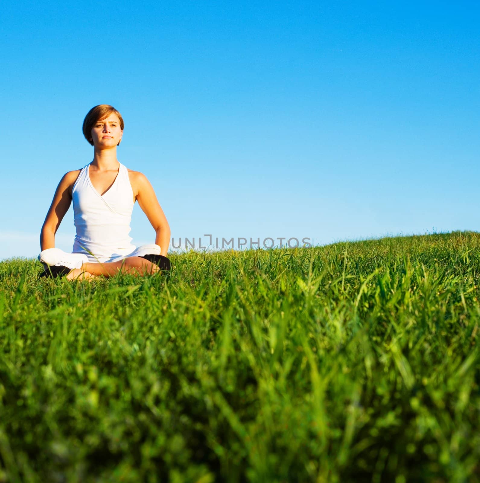 Young woman doing yoga in a sunny meadow, from a complete series of photos.