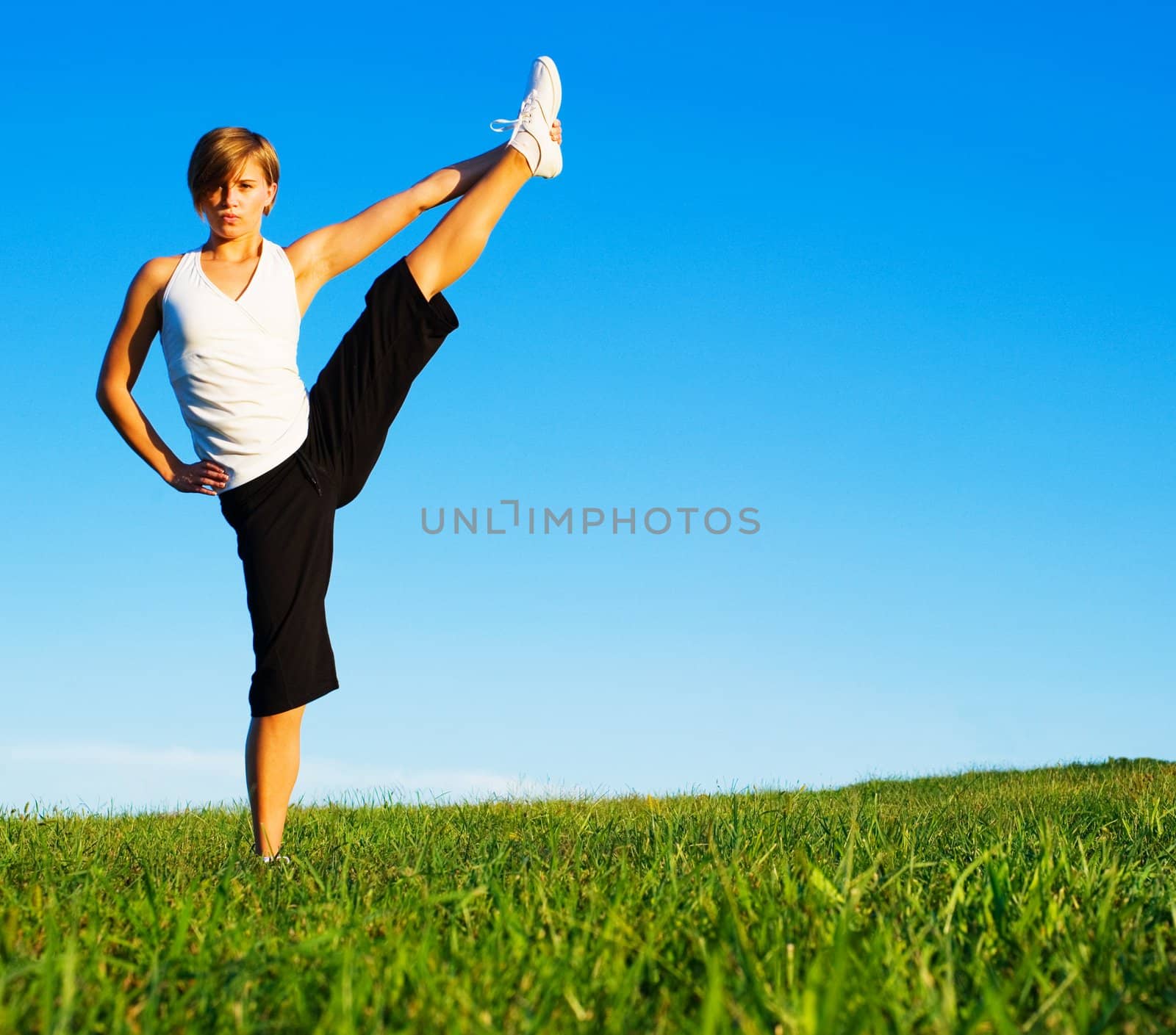 Young woman doing yoga in a sunny meadow, from a complete series of photos.