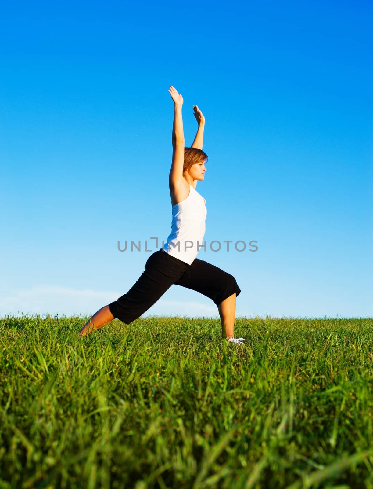 Young woman doing yoga in a sunny meadow, from a complete series of photos.