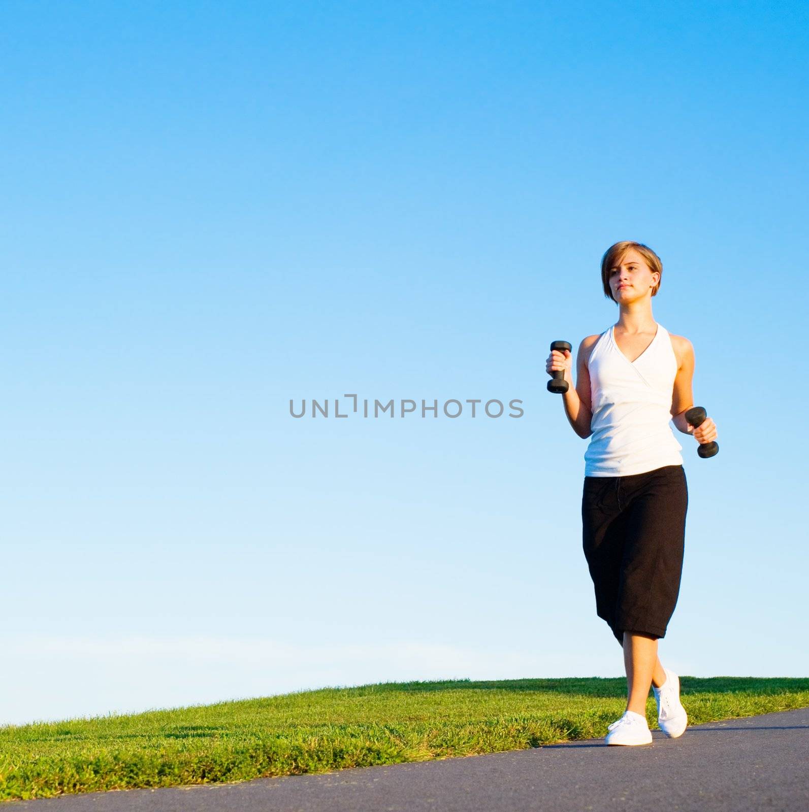 Young woman walking with weights, from a complete series of photos.