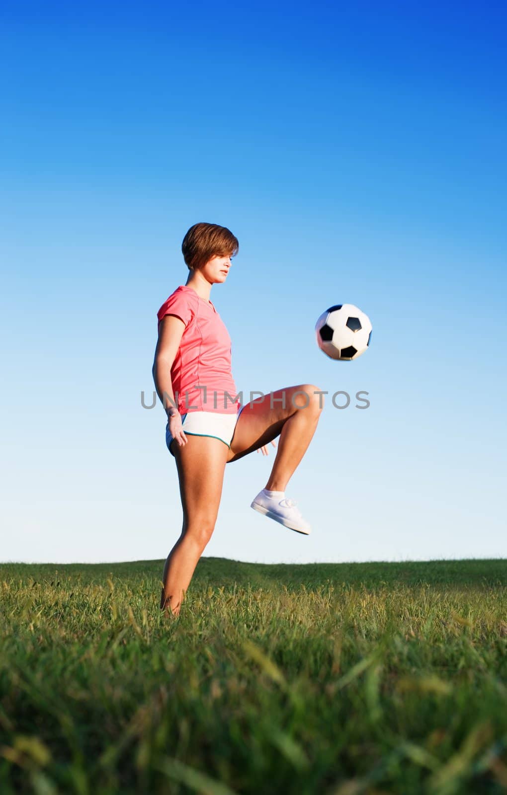 Young woman playing soccer in a field, from a complete series of photos.