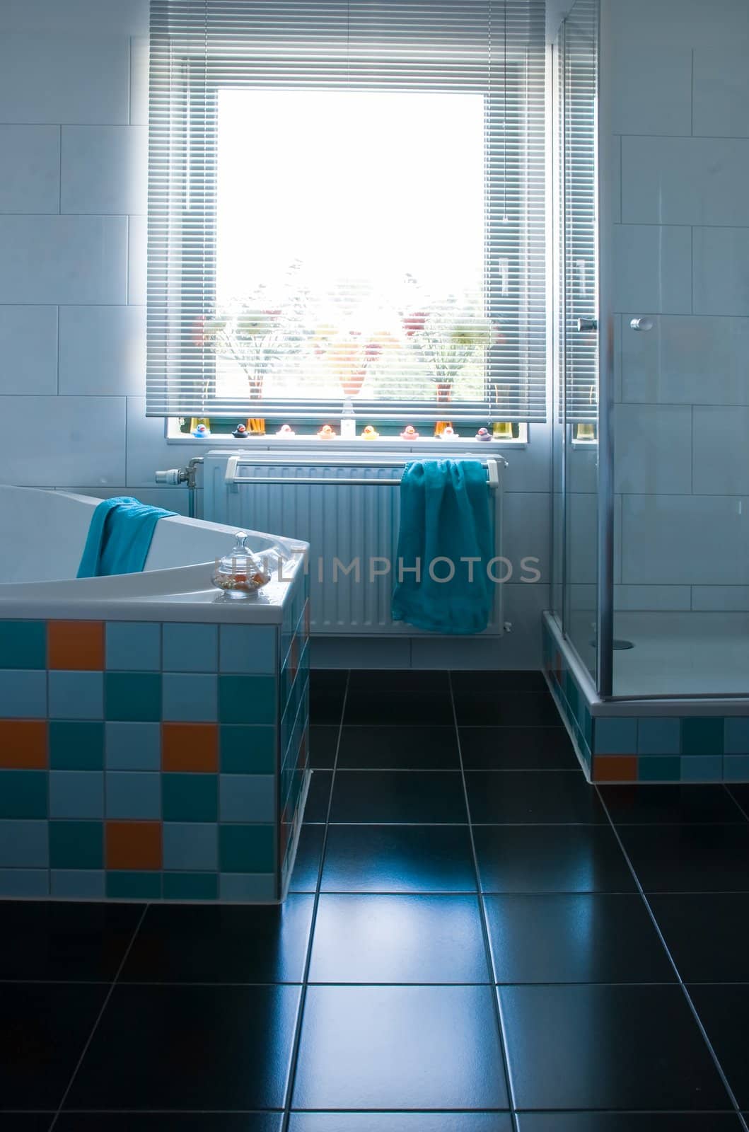 White bathroom, black floor, colorful decorated with tiles in light blue, azure blue and orange - vertical