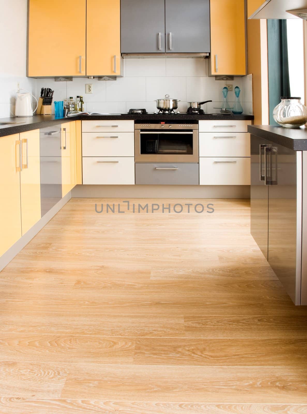 View into colorful modern kitchen in black, yellow and grey with wooden floor - vertical