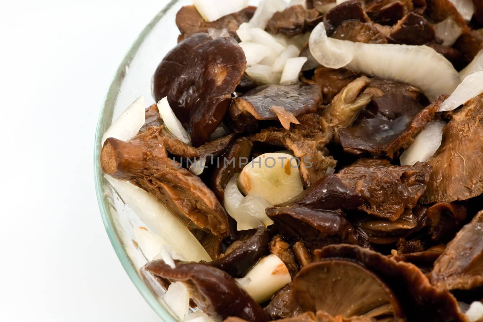 Salted mushrooms with sliced onion and olive oil in glass bowl 