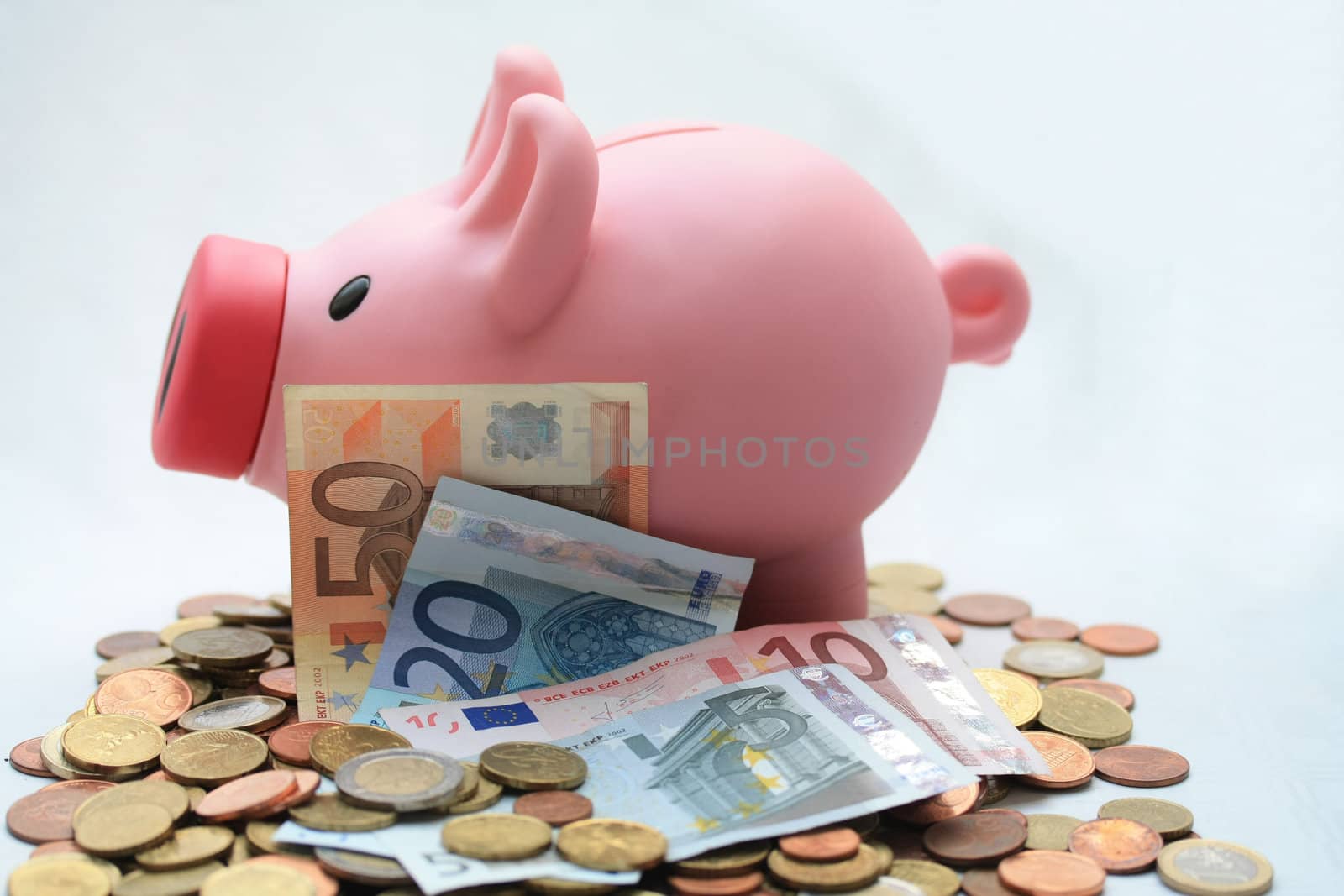 Piggy bank on a set of various euro coins and banknotes 