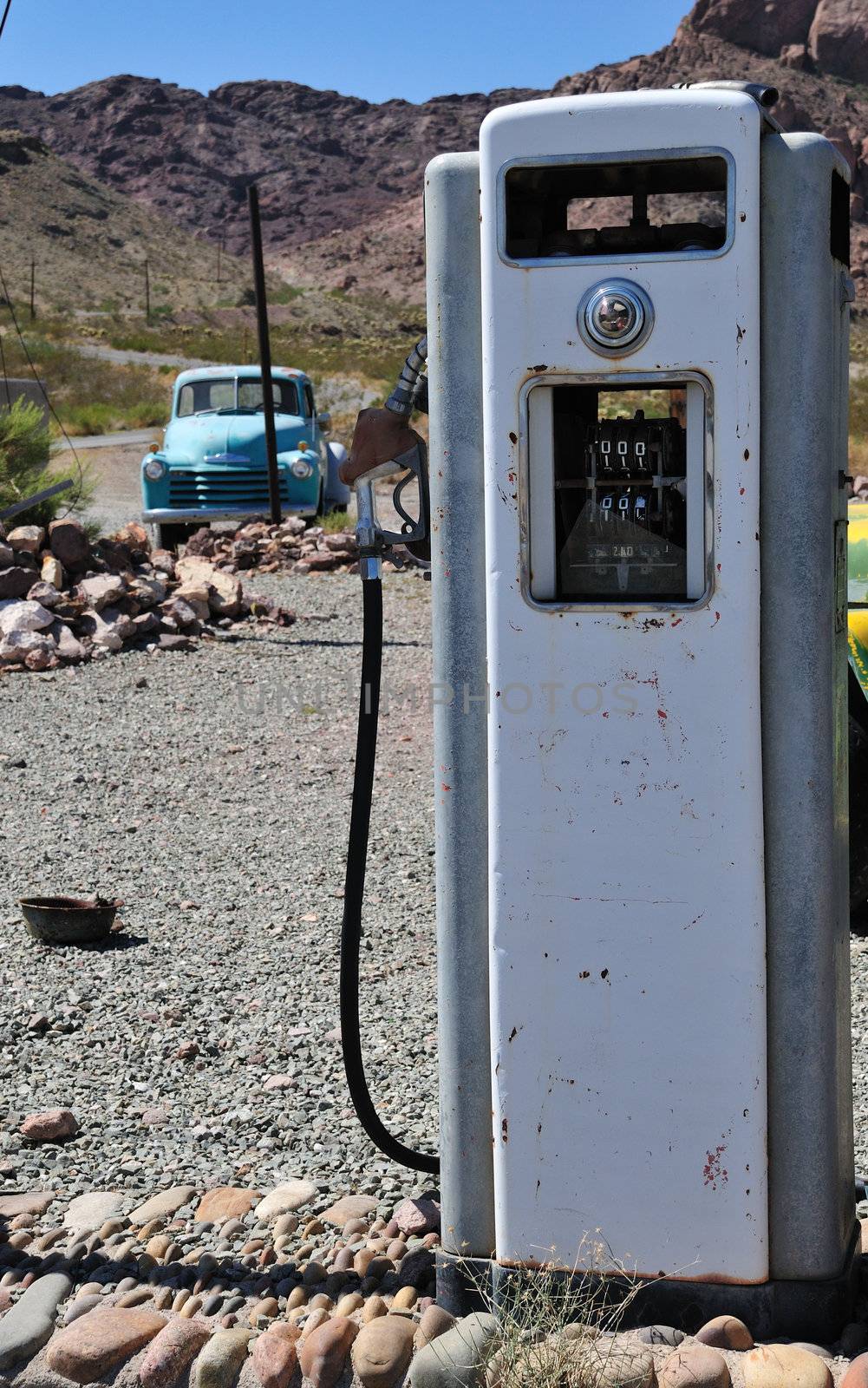old time vintage gas pump in the middle of no-where with mountain view and a beatup old truck