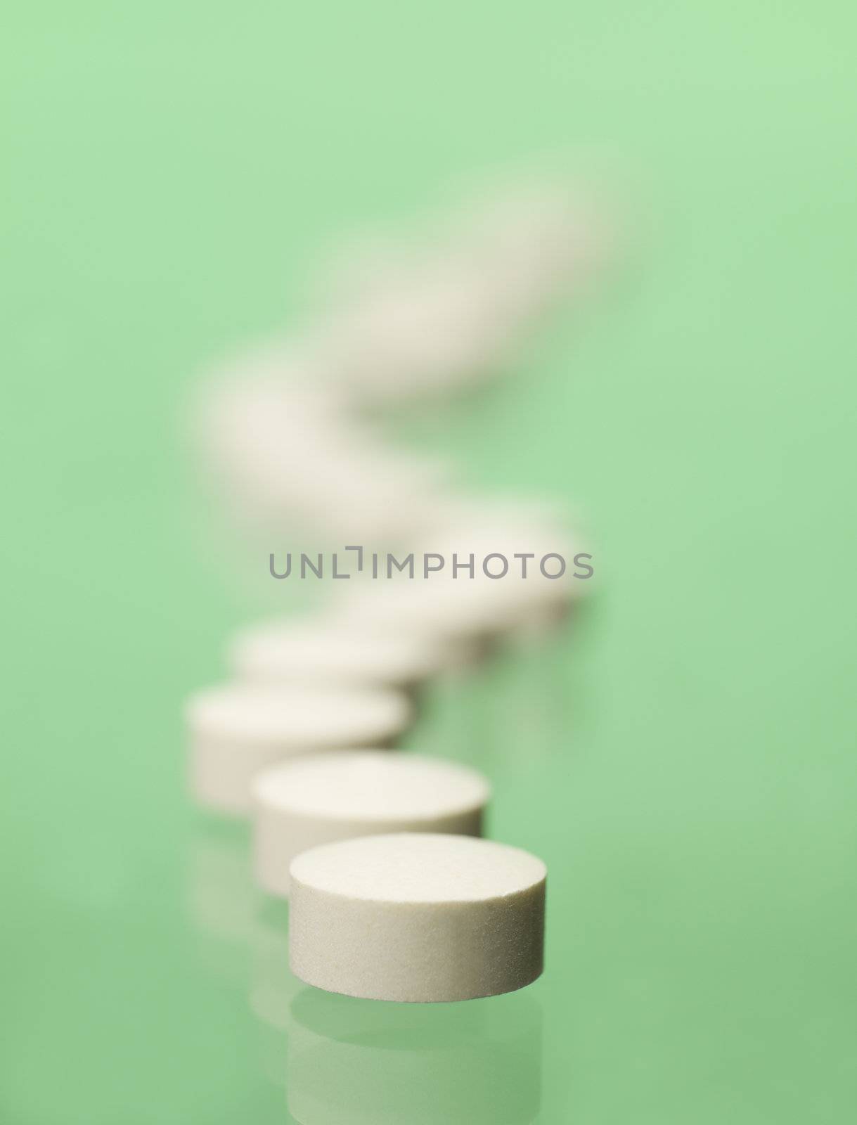 Pills in a row towards green background