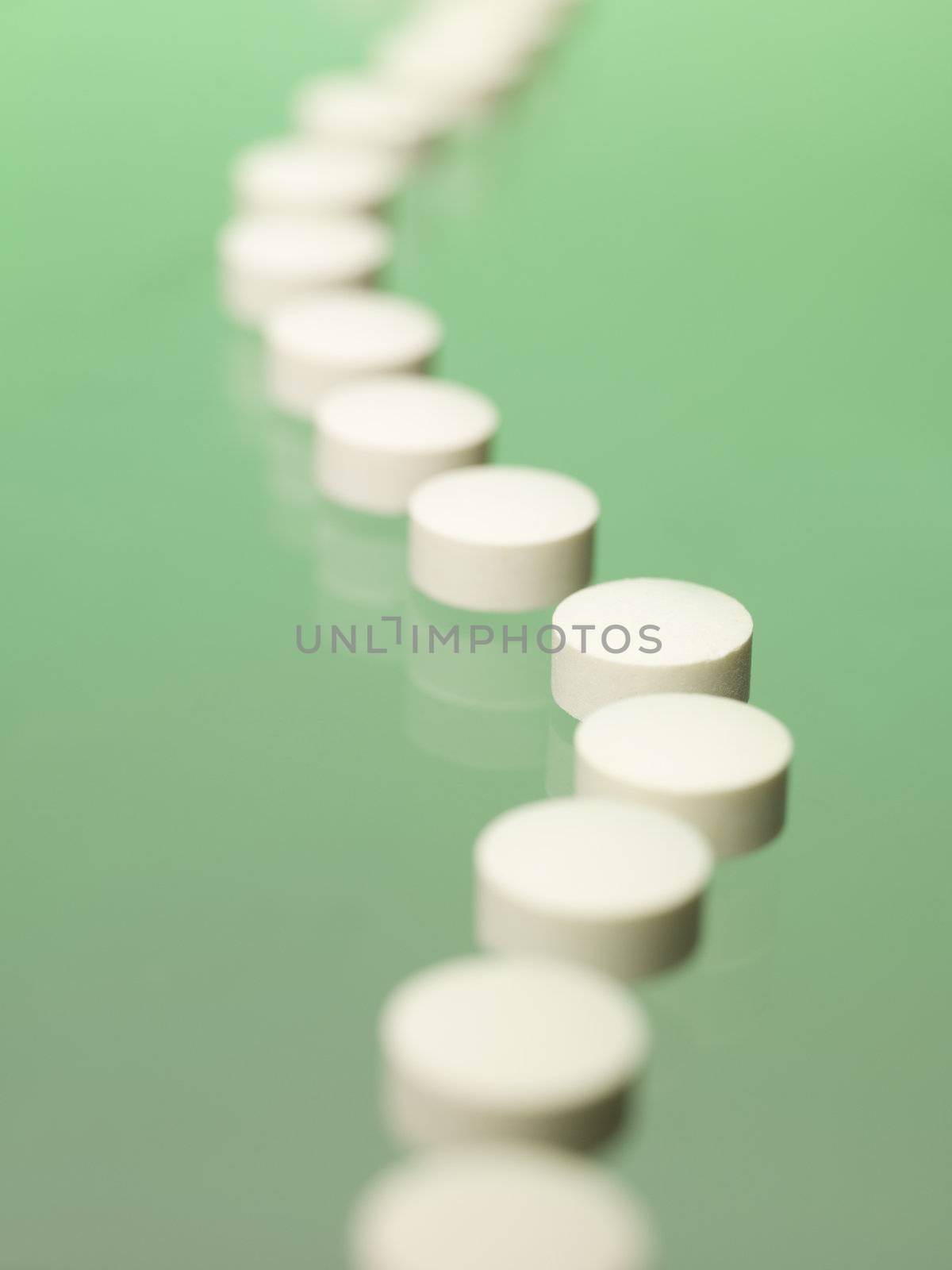 Pills in a row towards green background by gemenacom