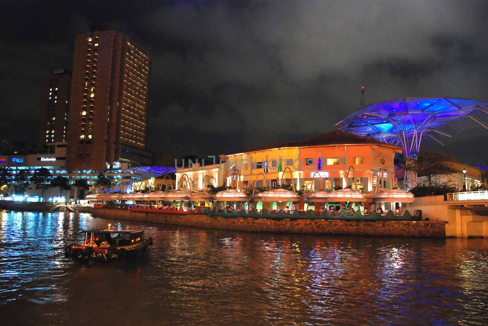 A boat crossing the Singapore River at night