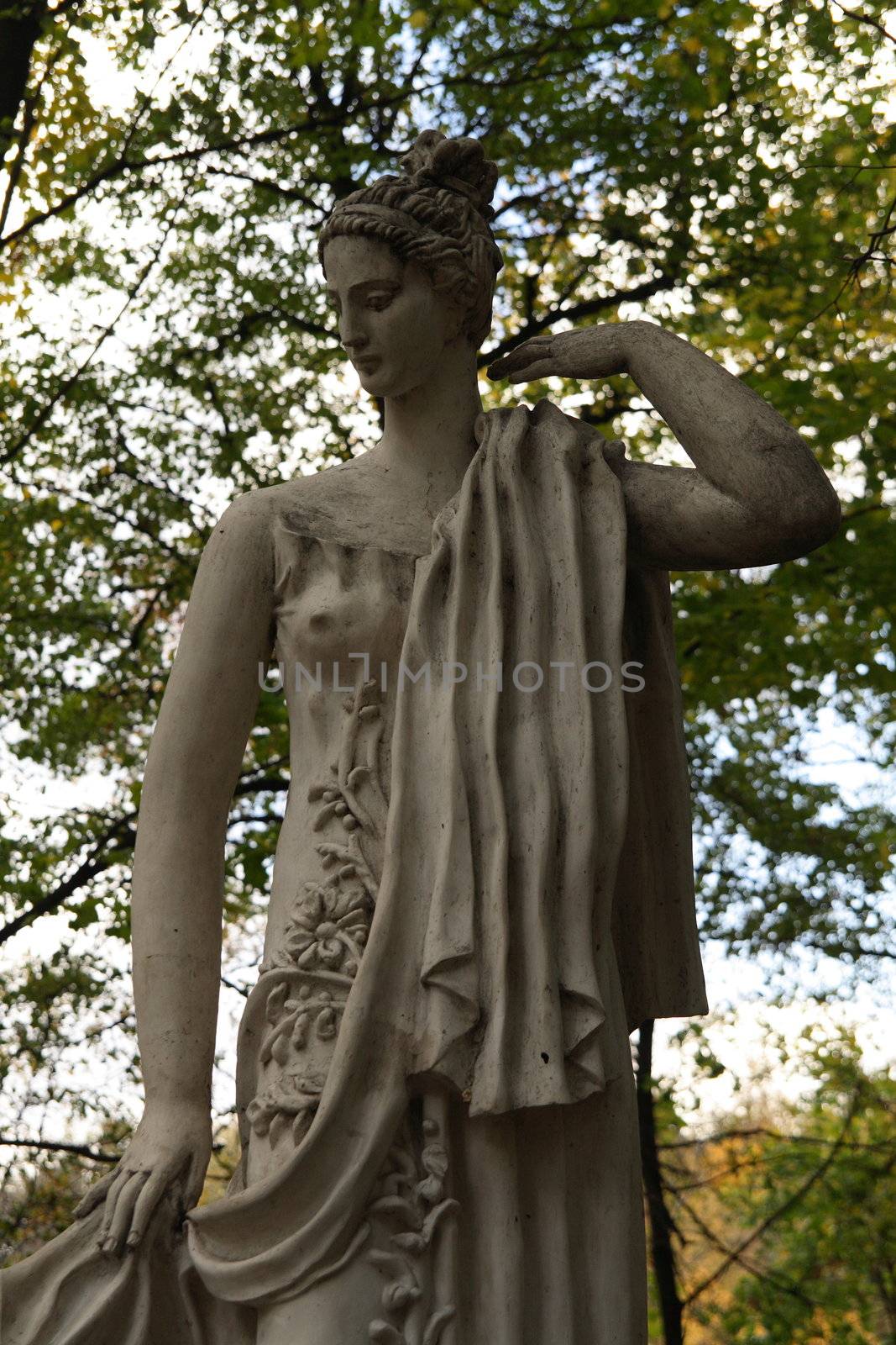 Ancient female statue in autumn park in three quarters